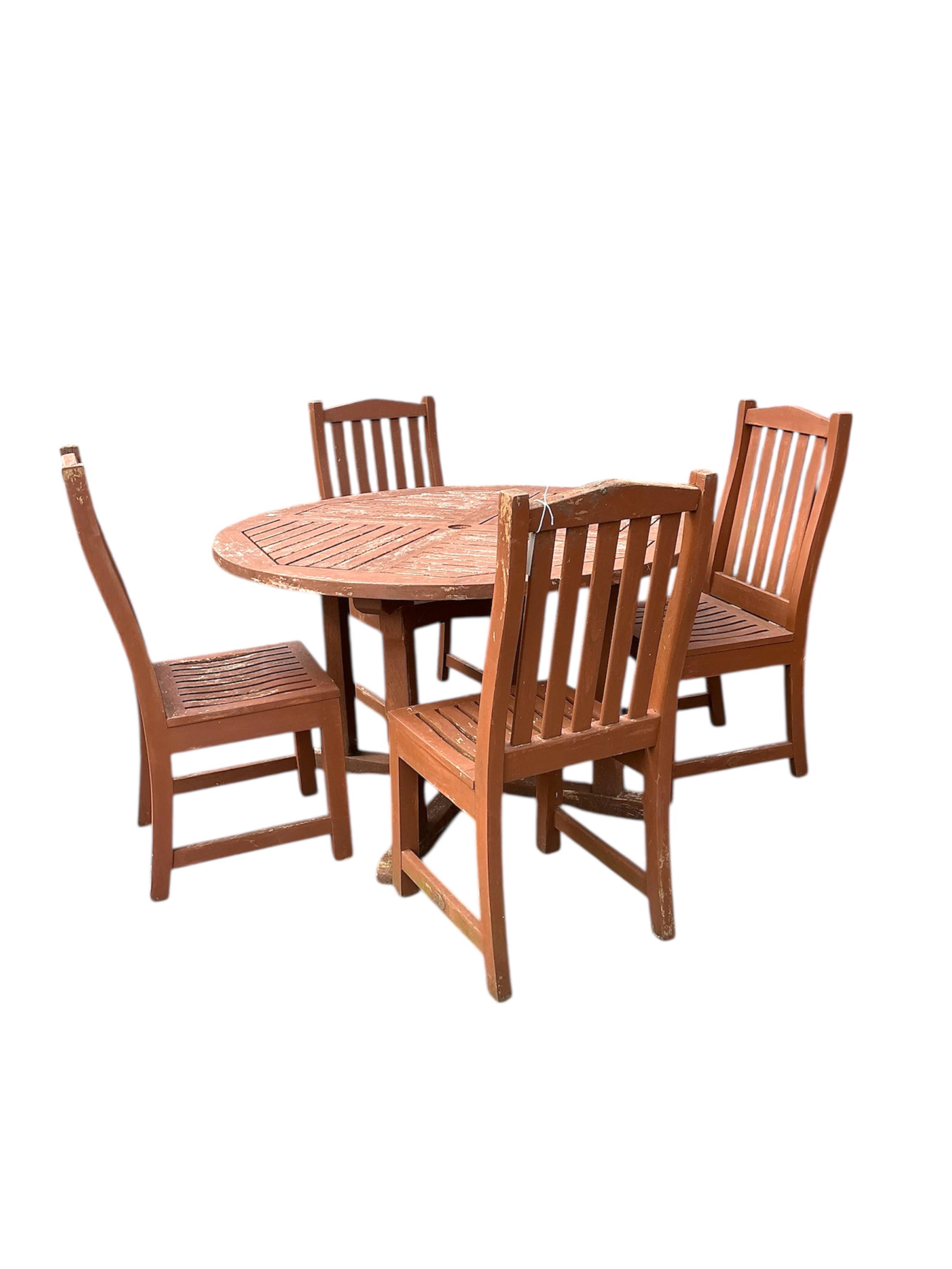 A circular stained teak garden table, diameter 121cm, height 73cm and four chairs